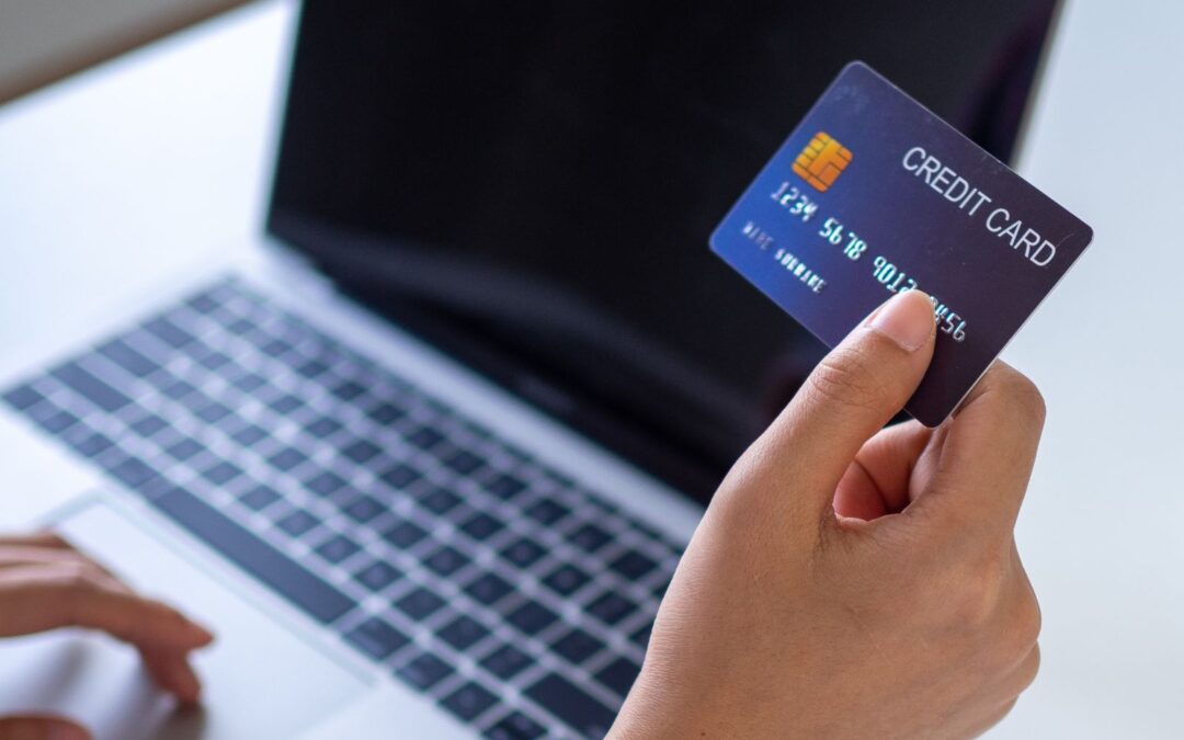 woman holding credit card in front of laptop